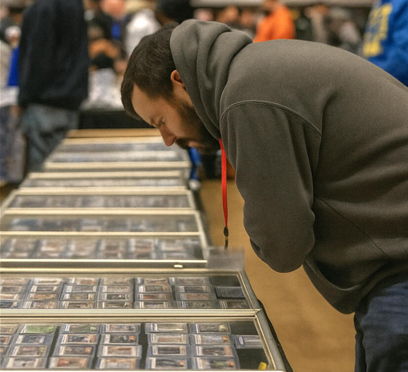 Collector browsing trading card display at a card show, representing Big Dawgs custom vinyl, kiss cut, and die cut stickers made for card shops and sellers.
